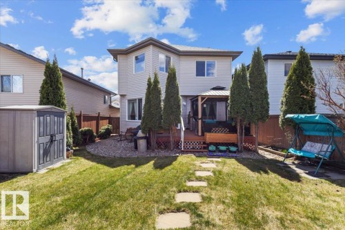 Manicured lawn with stepping stones leading to a spacious elevated deck featuring a gazebo - 3356 25 Ave, Edmonton, AB - Outdoor