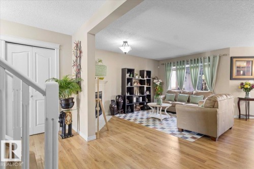 Open concept living area featuring wood-finish flooring, a contemporary ceiling light fixture, and a partial staircase with white railing - 3356 25 Ave, Edmonton, AB - Indoor Photo Showing Living Room