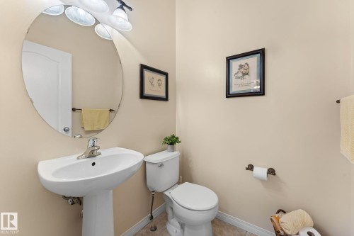 Pedestal sink with chrome faucet, oval mirror, and three-light vanity fixture - 112 Lakeland Point(E), Beaumont, AB - Indoor Photo Showing Bathroom