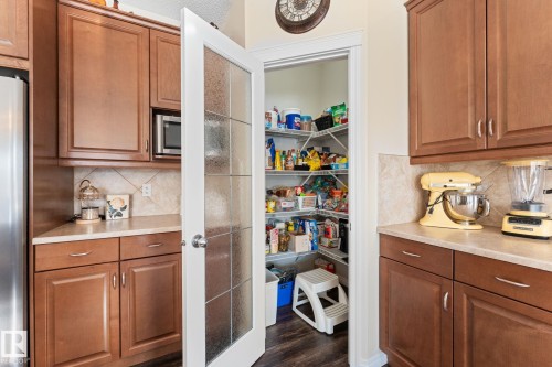 Kitchen pantry with a white frosted glass door, wood-finish flooring, and wire shelving - 112 Lakeland Point(E), Beaumont, AB - Indoor Photo Showing Kitchen