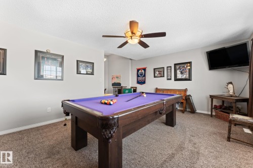 Recreation room featuring a pool table with a purple felt surface, textured carpeting, a ceiling fan with integrated lighting, and neutral wall paint - 112 Lakeland Point(E), Beaumont, AB - Indoor Photo Showing Other Room