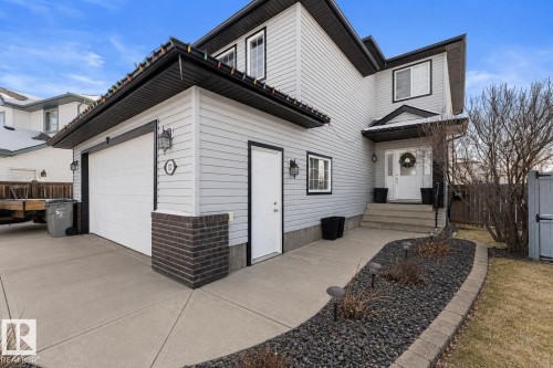Two-story residence featuring light gray siding with dark trim, a two-car garage, and a concrete driveway - 112 Lakeland Point(E), Beaumont, AB - Outdoor