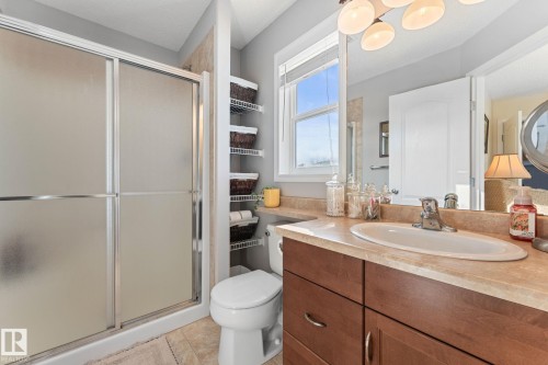 Bathroom featuring a frosted glass shower enclosure, a single vanity with a light-colored countertop, and a window with blinds - 112 Lakeland Point(E), Beaumont, AB - Indoor Photo Showing Bathroom