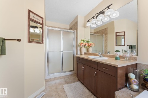 Bathroom featuring a vanity with a light-colored countertop, integrated sink, and dark wood-finish cabinetry - 112 Lakeland Point(E), Beaumont, AB - Indoor Photo Showing Bathroom