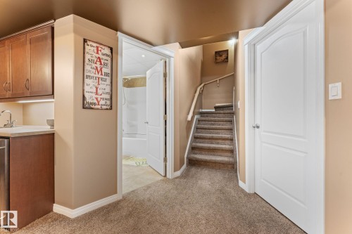 Lower-level space featuring wood-finish cabinetry, a stainless-steel sink, and a built-in appliance - 112 Lakeland Point(E), Beaumont, AB - Indoor