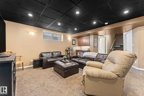 Lower-level living space featuring a black grid ceiling with recessed lighting, beige walls, and carpet flooring - 112 Lakeland Point(E), Beaumont, AB - Indoor Photo Showing Basement