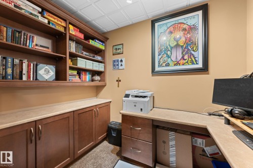 Built-in cabinetry with wood-finish doors and drawers, featuring extensive shelving, light-toned countertops, and a textured ceiling - 112 Lakeland Point(E), Beaumont, AB - Indoor Photo Showing Office