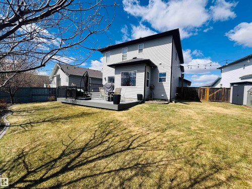 Expansive backyard featuring a multi-level composite deck with dark railings, a manicured lawn, and a privacy fence - 112 Lakeland Point(E), Beaumont, AB - Outdoor