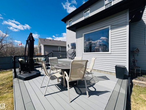 Expansive multi-level composite deck featuring dark railings, a large picture window, and light gray siding - 112 Lakeland Point(E), Beaumont, AB - Outdoor With Deck Patio Veranda