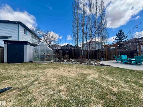Spacious backyard featuring a large shed, a greenhouse, a rock garden, a concrete patio, and a wooden pergola - 112 Lakeland Point(E), Beaumont, AB - Outdoor