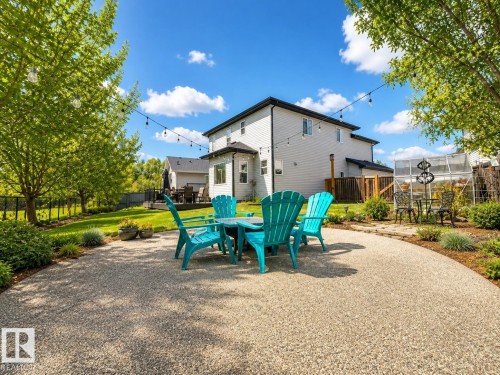 Spacious backyard featuring a gravel patio, string lighting, mature trees, and a manicured lawn - 112 Lakeland Point(E), Beaumont, AB - Outdoor