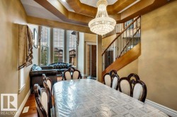Formal dining area featuring a tiered tray ceiling with a prominent crystal chandelier - 