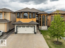 Stucco exterior with stone accents, featuring a prominent two-car garage and a paved driveway - 