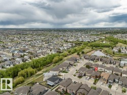 Expansive neighborhood featuring numerous residential properties, mature trees, and a visible pond surrounded by natural elements - 