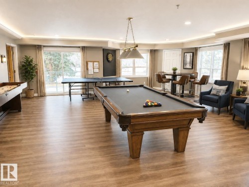 Spacious recreation room featuring wood-finish flooring, recessed lighting, and multiple windows - 219 9535 176 Street, Edmonton, AB - Indoor Photo Showing Other Room