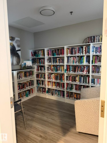 Dedicated library room featuring extensive built-in shelving, wood-finish flooring, and recessed overhead lighting - 219 9535 176 Street, Edmonton, AB - Indoor Photo Showing Office