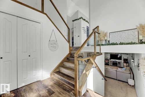 Staircase featuring wood-finish treads and risers, glass panel railings, and wood-finish handrails - 3208 135A Avenue, Edmonton, AB - Indoor Photo Showing Other Room
