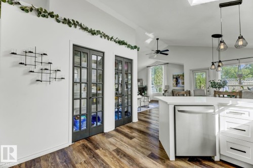 Kitchen island with a built-in stainless steel dishwasher, white cabinetry, and pendant lighting - 3208 135A Avenue, Edmonton, AB - Indoor