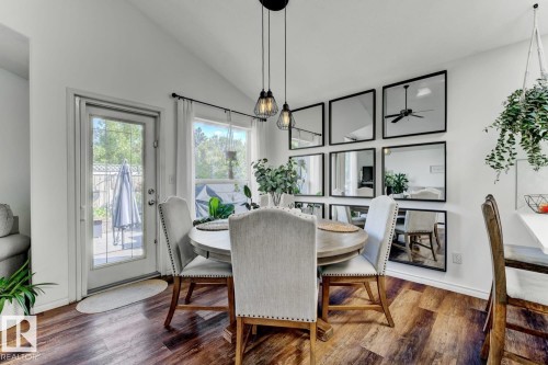 Vaulted ceiling dining area featuring wood-finish flooring, a glass-paned door, and a multi-paneled mirror wall accent - 3208 135A Avenue, Edmonton, AB - Indoor Photo Showing Dining Room
