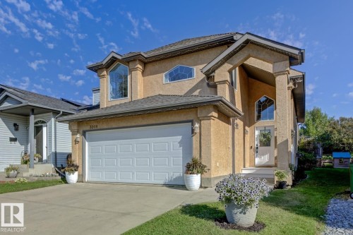 Stucco exterior with a prominent front entrance featuring a covered porch, arched transom window, and a white paneled door - 3208 135A Avenue, Edmonton, AB - Outdoor With Facade