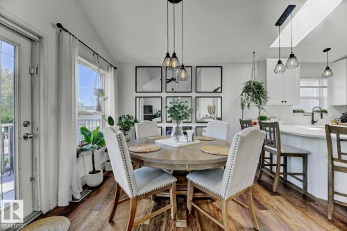 Dining area featuring wood-finish flooring, a contemporary chandelier, and a white paneled door with glass inserts - 3208 135A Avenue, Edmonton, AB - Indoor Photo Showing Dining Room