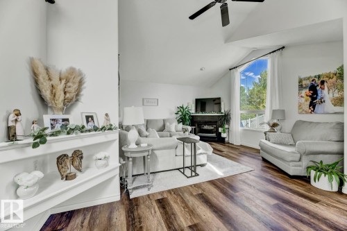 Vaulted ceiling living area featuring wood-finish flooring, a contemporary ceiling fan, and a built-in fireplace with a mantel - 3208 135A Avenue, Edmonton, AB - Indoor Photo Showing Living Room