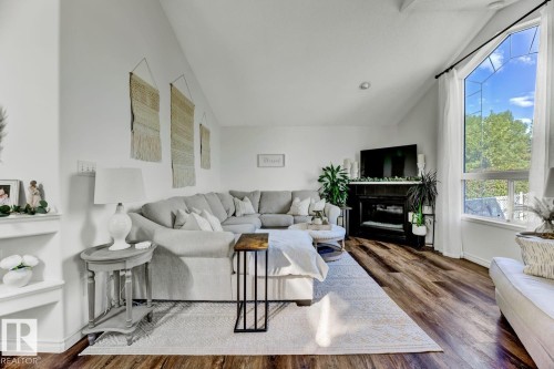 Spacious living area featuring high vaulted ceilings, expansive windows, a built-in fireplace, warm wood-finish flooring, and integrated shelving - 3208 135A Avenue, Edmonton, AB - Indoor Photo Showing Living Room