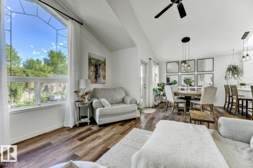 Open-concept living space featuring wood-finish flooring, a large picture window, vaulted ceilings, and a ceiling fan - 3208 135A Avenue, Edmonton, AB - Indoor Photo Showing Living Room