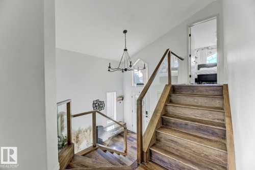 Wood-finish staircase with transparent panel railings - 3208 135A Avenue, Edmonton, AB - Indoor Photo Showing Other Room