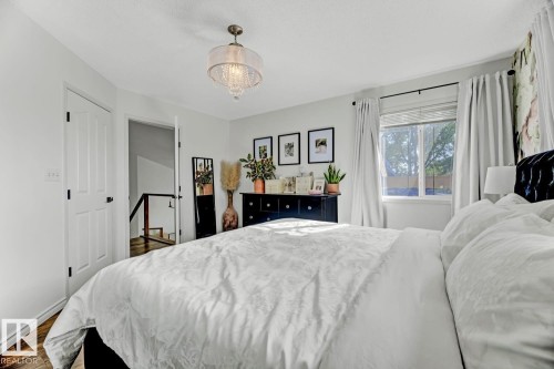 Bedroom featuring wood-finish flooring, a white paneled door, and a multi-pane window - 3208 135A Avenue, Edmonton, AB - Indoor Photo Showing Bedroom