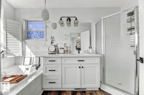 Bathroom featuring a white vanity with countertop, framed mirror, and modern lighting fixture - 3208 135A Avenue, Edmonton, AB - Indoor