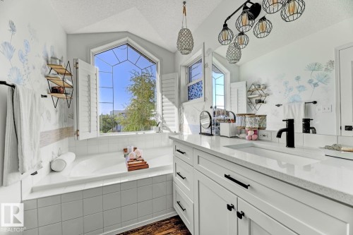 Soaking tub with white tile surround and shuttered bay window - 3208 135A Avenue, Edmonton, AB - Indoor Photo Showing Bathroom