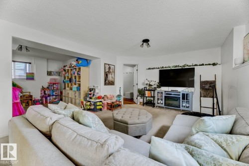 Bright living space featuring a recessed area with a window, a built-in entertainment console with an electric fireplace, and overhead track lighting - 3208 135A Avenue, Edmonton, AB - Indoor Photo Showing Living Room