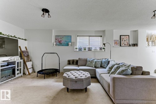 Carpeted living space with recessed window, built-in shelving, and white walls - 3208 135A Avenue, Edmonton, AB - Indoor Photo Showing Living Room