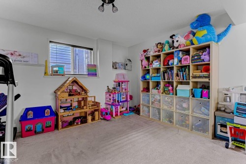 Carpeted room featuring a window with horizontal blinds, overhead ceiling light fixture, and a built-in modular shelving unit - 3208 135A Avenue, Edmonton, AB - Indoor