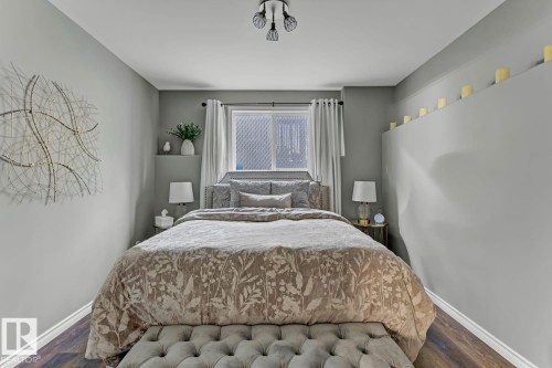 Bedroom featuring wood-finish flooring, a contemporary ceiling fixture, a window with curtains, and a built-in architectural shelf - 3208 135A Avenue, Edmonton, AB - Indoor Photo Showing Bedroom