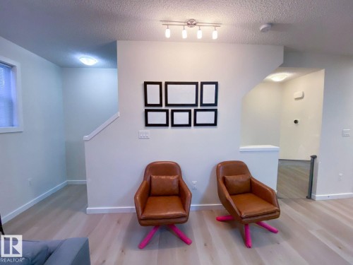 Open living area featuring wood-finish flooring, light-colored walls, and a track lighting fixture - 118 655 Watt Boulevard, Edmonton, AB - Indoor Photo Showing Other Room