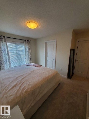 Carpeted room featuring a ceiling-mounted light fixture, neutral wall paint, and white trim - 118 655 Watt Boulevard, Edmonton, AB - Indoor Photo Showing Bedroom