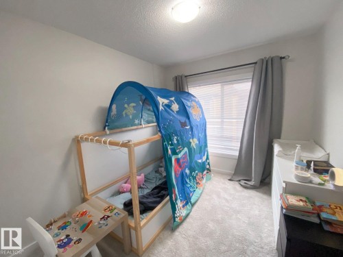 Light-filled room featuring neutral wall paint, a single window with blinds and drapes, and light-toned carpeting - 118 655 Watt Boulevard, Edmonton, AB - Indoor