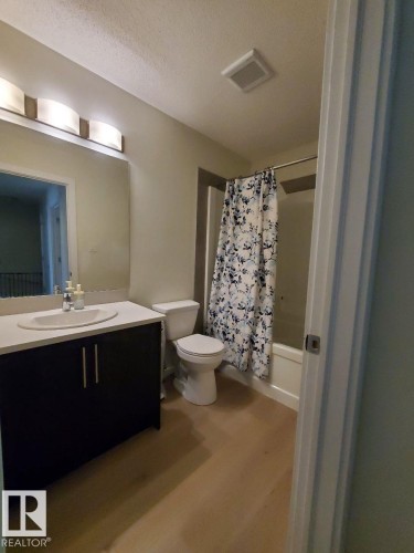 Full bathroom featuring a single vanity with a dark wood-finish cabinet, white countertop, and integrated sink - 118 655 Watt Boulevard, Edmonton, AB - Indoor Photo Showing Bathroom
