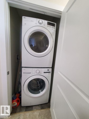 Dedicated laundry area featuring a stacked washer and dryer unit within a closet - 118 655 Watt Boulevard, Edmonton, AB - Indoor Photo Showing Laundry Room
