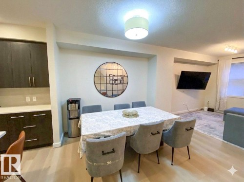 Open-concept dining area featuring wood-finish flooring, a contemporary ceiling light fixture, and a built-in cabinetry system with light countertops - 118 655 Watt Boulevard, Edmonton, AB - Indoor Photo Showing Dining Room