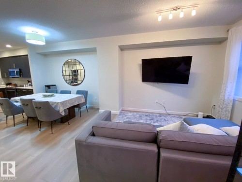 Open-concept living area featuring light wood-finish flooring, recessed wall niche, track lighting, and a modern drum pendant light - 118 655 Watt Boulevard, Edmonton, AB - Indoor Photo Showing Living Room