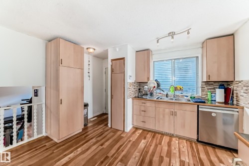 Kitchen area featuring wood-finish flooring, light wood cabinetry, and a patterned tile backsplash - 1804 51 Street Nw, Edmonton, AB - Indoor Photo Showing Kitchen With Double Sink