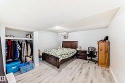Spacious room featuring light wood-finish flooring, white walls, and a built-in closet with shelving and hanging space - 