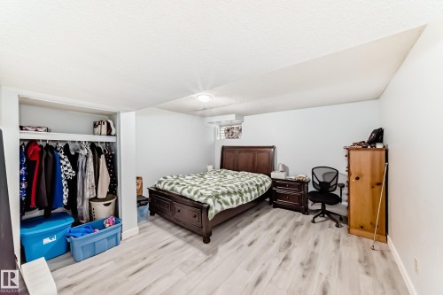Spacious room featuring light wood-finish flooring, white walls, and a built-in closet with shelving and hanging space - 1804 51 Street Nw, Edmonton, AB - Indoor Photo Showing Bedroom