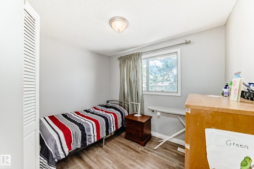 Room featuring wood-finish flooring, a window with exterior views, and a louvered bi-fold closet door - 1804 51 Street Nw, Edmonton, AB - Indoor Photo Showing Bedroom