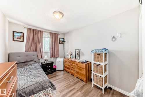Bedroom with wood-finish flooring, a window featuring blinds and drapery, and a ceiling-mounted light fixture - 1804 51 Street Nw, Edmonton, AB - Indoor Photo Showing Bedroom