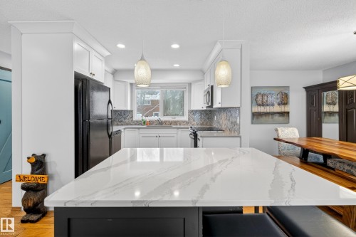 The kitchen features white cabinetry, a white countertop island, and a mosaic tile backsplash - 17 Austin Crescent, St. Albert, AB - Indoor Photo Showing Kitchen With Upgraded Kitchen