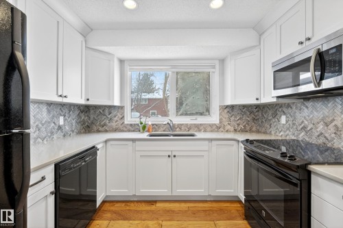Kitchen featuring white cabinetry, a herringbone pattern backsplash, and a window above the sink - 17 Austin Crescent, St. Albert, AB - Indoor Photo Showing Kitchen With Double Sink